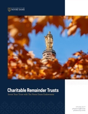 Golden statue of Mary on Notre Dame's Golden Dome, framed by bright orange autumn leaves against a blue sky.